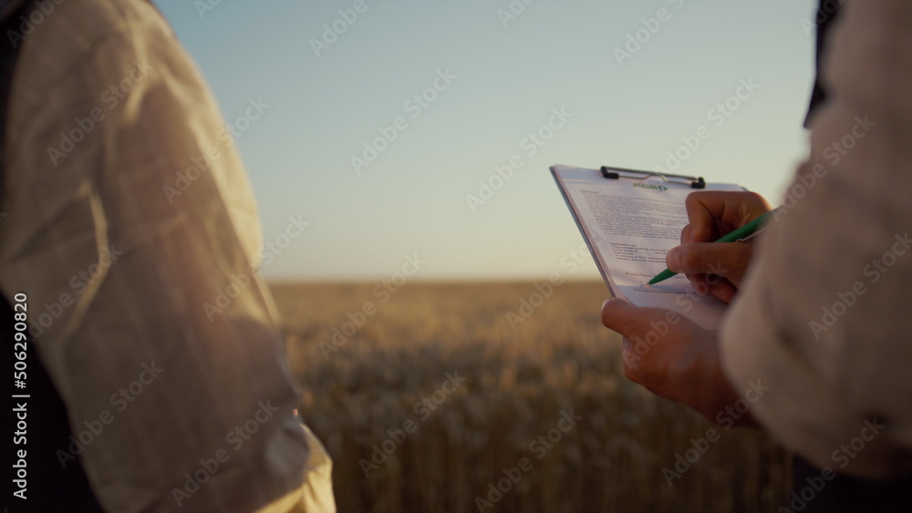 Partners signing contract wheat field. Farmers hands hold clipboard close up.