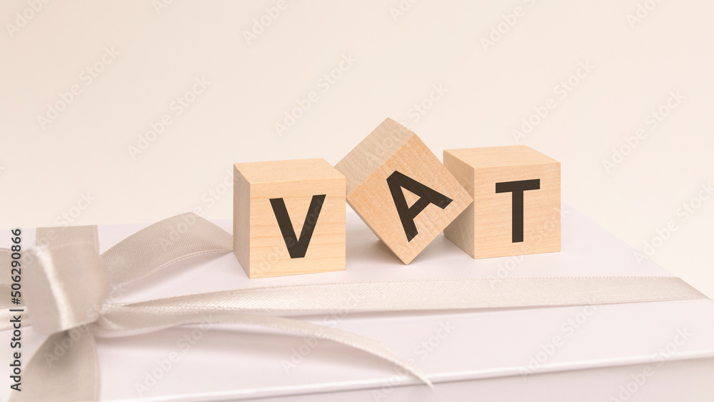 three cubes with text vat on the white surface of a gift box tied with a light festive ribbon three cubes with text vat on the white surface of a gift box tied with a light festive ribbon