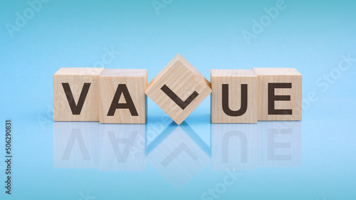 Value - word is written on wooden cubes on a bright blue background. close-up of wooden elements