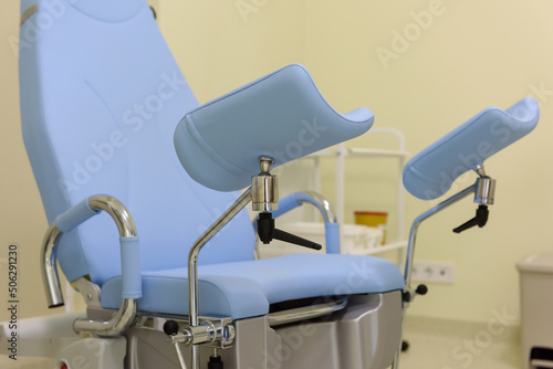 Gynecological chair in a modern gynecologist's office. Empty gynecological bed in the obstetrics and gynecology department. Clinic or hospital interior. Modern medical equipment and tools close-up. photo