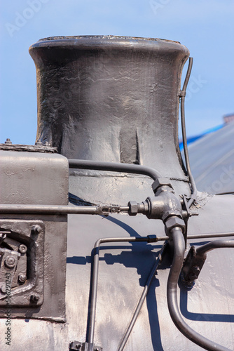 View of the smokestack of an old steam locomotive close-up. Vertical pipe on top of the smokebox that ejects the steam