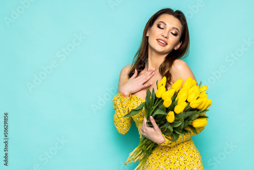 Young beautiful woman with bouquet of yellow flowers on green background