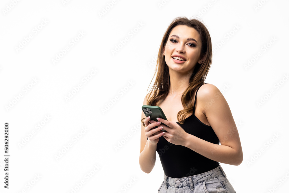 Photo of a shocked surprised young woman posing isolated over white wall background using mobile phone. Photo of a shocked surprised young woman posing isolated over white wall background using mobile phone.