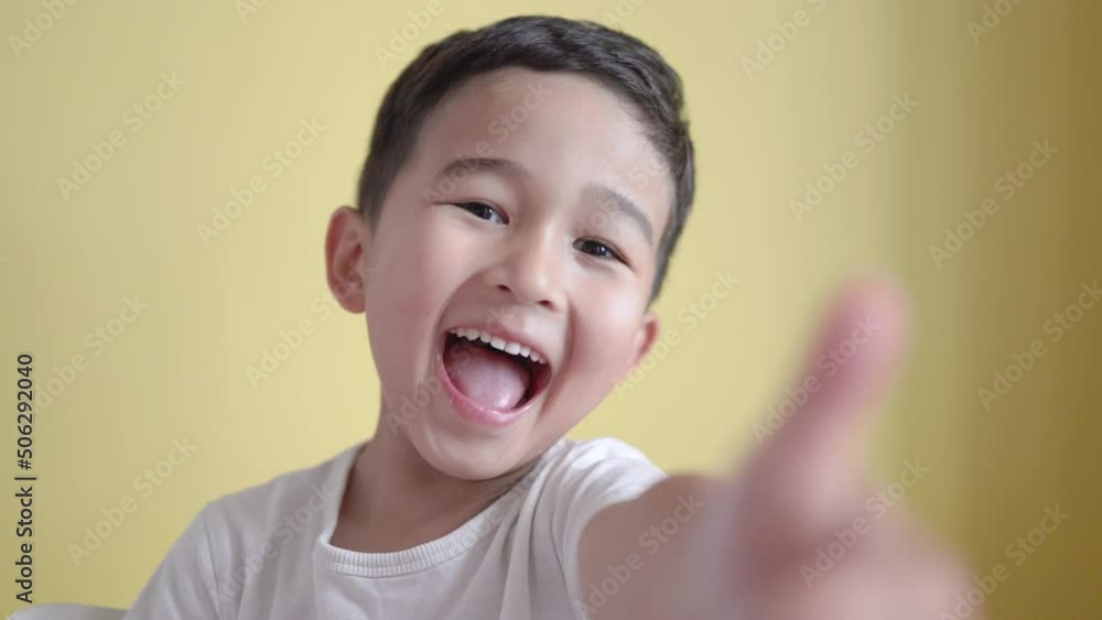 Cheerful preschooler smiling and showing thumbs up on colour background Cheerful preschooler smiling and showing thumbs up on colour background