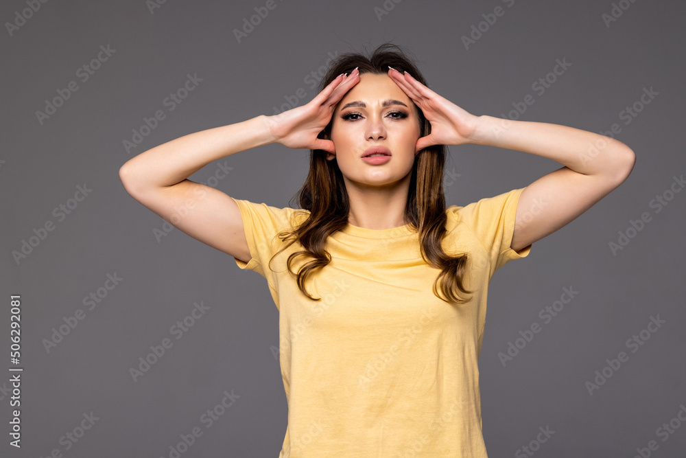 Angry woman covers her ears with hands and shouting while standing isolated over gray background Angry woman covers her ears with hands and shouting while standing isolated over gray background