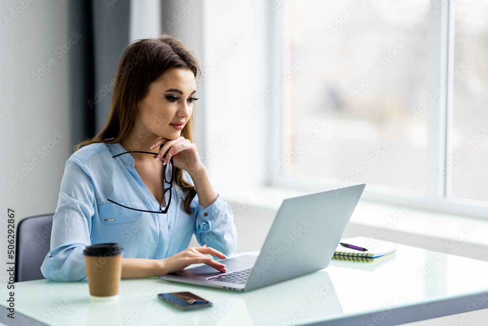 Young woman smiling while working with laptop in office Young woman smiling while working with laptop in office