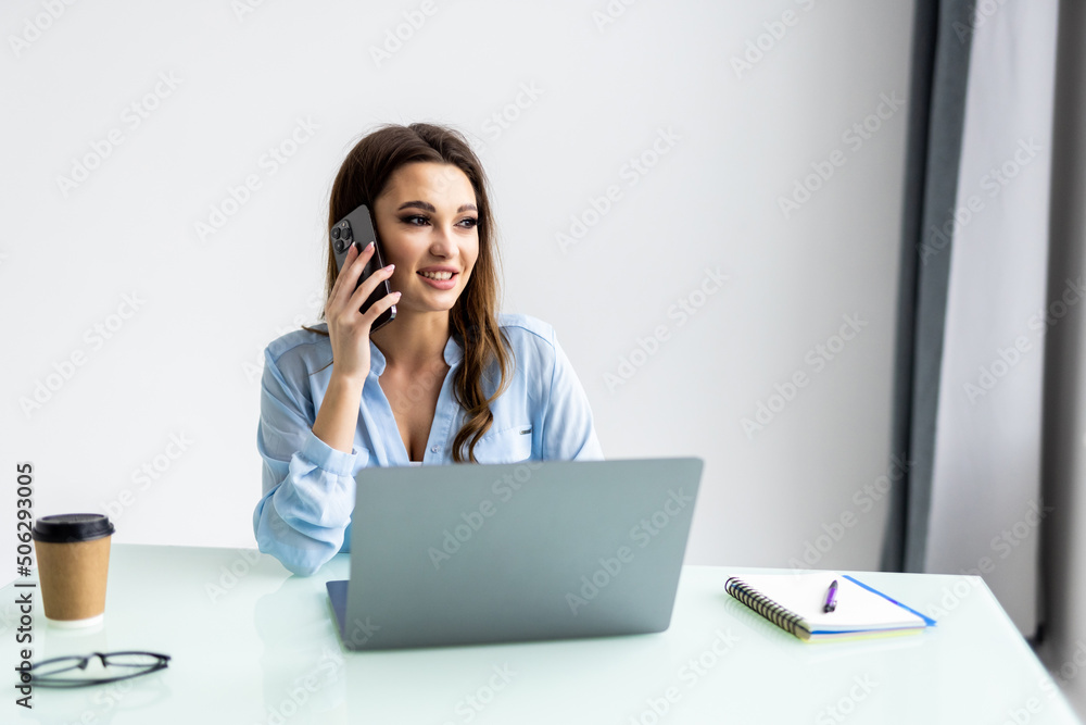 Portrait of beautiful executive woman making call while sitting at her workplace in front of laptop and working on new project. Portrait of beautiful executive woman making call while sitting at her workplace in front of laptop and working on new project.