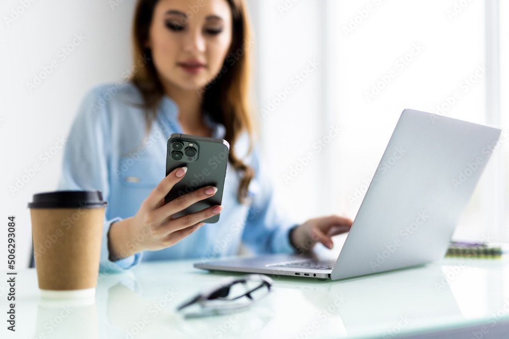Excited businesswoman talking on smartphone, sitting at desk with laptop, friendly young woman freelancer consulting client by phone call negotiating, discussing project with colleague, multitasking Excited businesswoman talking on smartphone, sitting at desk with laptop, friendly young woman freelancer consulting client by phone call negotiating, discussing project with colleague, multitasking