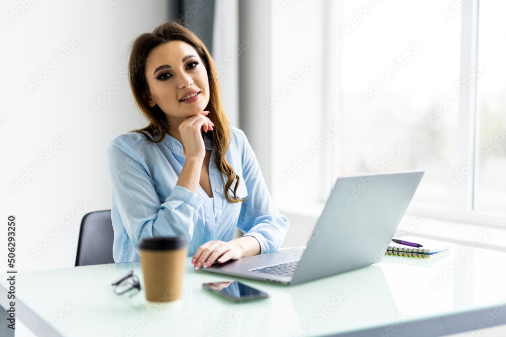 Young beautiful businesswoman working on laptop in bright modern office Young beautiful businesswoman working on laptop in bright modern office