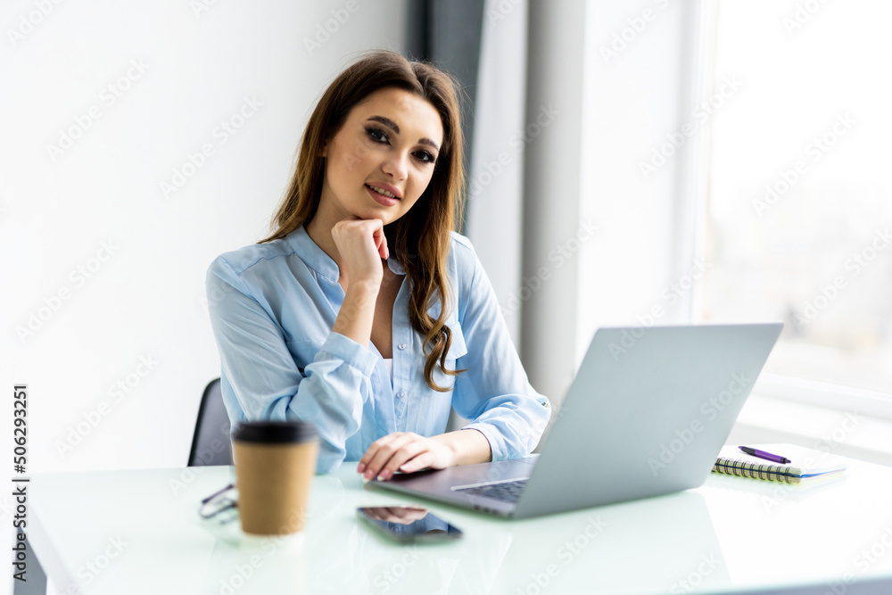 Business woman in shirt using laptop computer and sitting by the table in office Business woman in shirt using laptop computer and sitting by the table in office