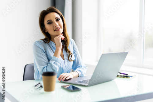 Young beautiful businesswoman working on laptop in bright modern office