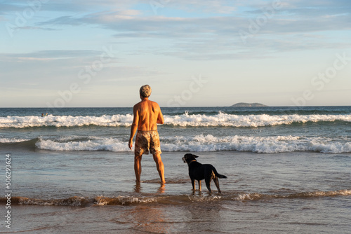 Man enjoying on the beach with his dog at sunset, Buzios, Brasil. photo
