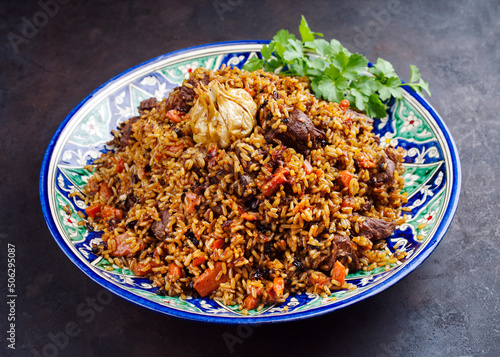 Traditional Uzbek fergana plov with devsira rice and lamb meat served as close-up on a handmade painted lagan platter photo