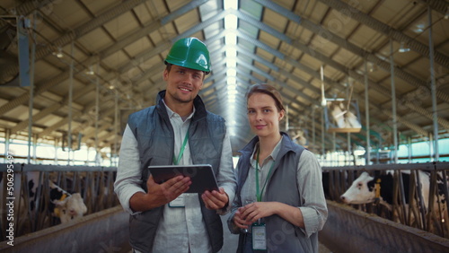 Livestock workers posing cowshed together. Holstein cows eating in feedlots.