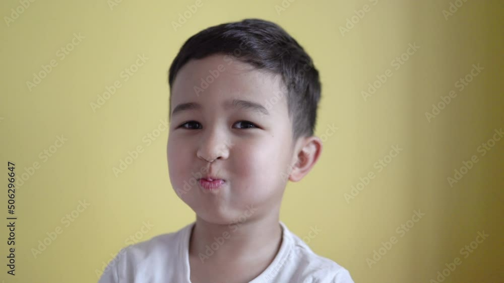 Cute boy looking at camera and grimaces on colour background Cute boy looking at camera and grimaces on colour background