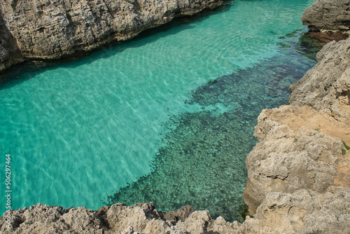 Large pool of turquoise blue waters on the bottom of the transparent sea, located between rocks. CopySpace. Balearic Islands, Spain.