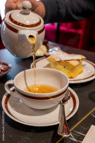 Tea time in England, pouring of black earl grey tea with bergamot in cafe in London, high tea