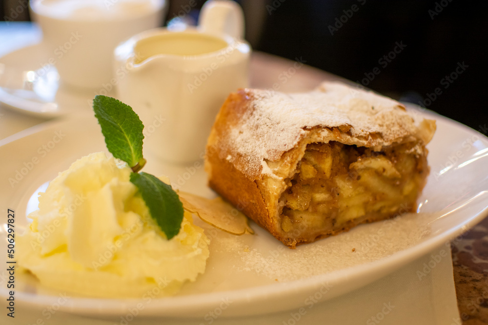 Austrian sweet dessert, portion of apple strudel with whippen cream and hot vanilla sauce served in old bakery cafe in Vienna, Austria