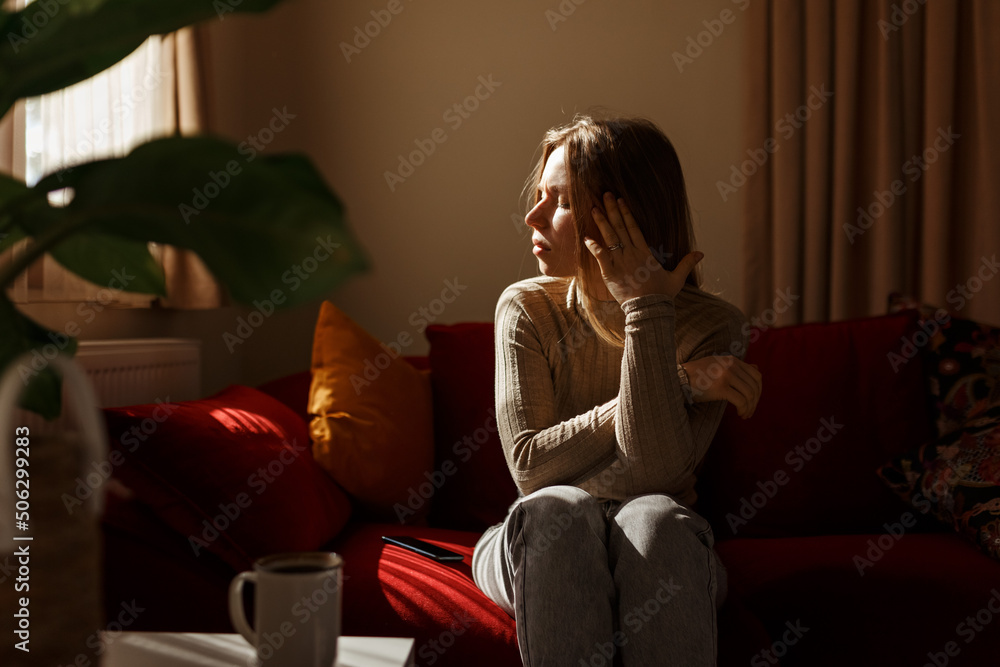Obraz premium Lady lying touching temples.Young woman suffering headache, migraine, depression, sitting on sofa, home interior.