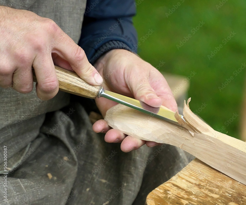An artisan makes a wooden spoon. Selective focus.