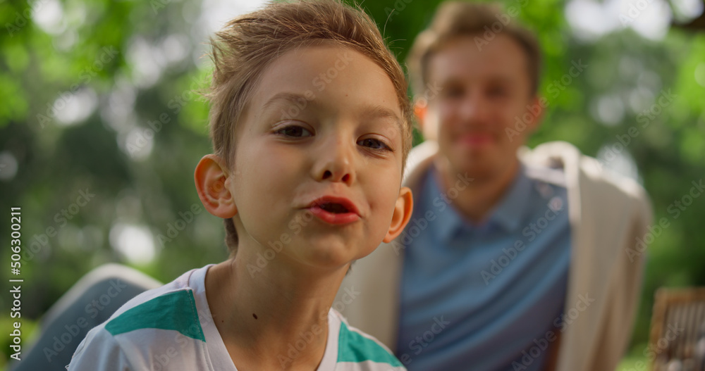 Eating boy smiling on camera on picnic closeup. Portrait of funny kid on nature 