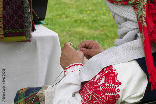 Woman in a national costume knits with needles. Selective focus. photo