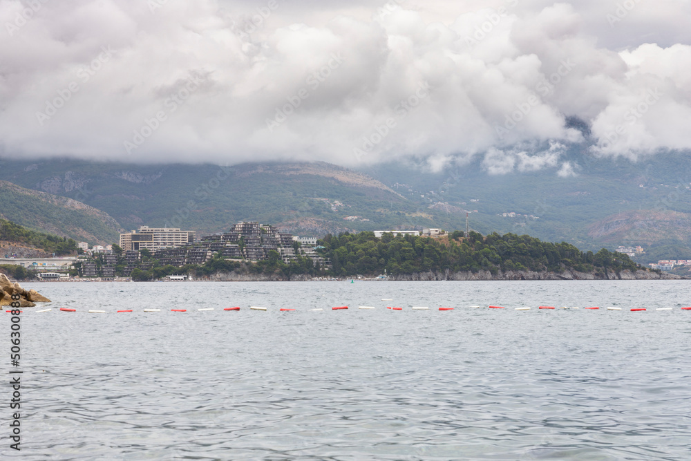 Obraz premium Budva, Montenegro - August 26, 2021: View of Budva town, Luxury travel destination with beatuiful beaches at Adriatic sea with amazing mountainscape covered in clouds