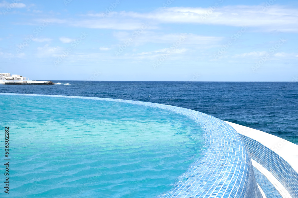 Blue clear water surface in swimming pool in a resort with sea views. Summer Vacation and rest concept. Luxury beach villa house. Blue tile mosaic pattern.