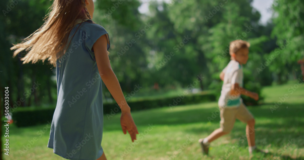 Pretty sister overtake brother on lawn. Happy family playing catch-up on meadow. Pretty sister overtake brother on lawn. Happy family playing catch-up on meadow.
