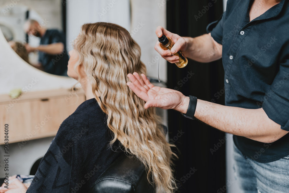 Fototapeta premium Beautiful blonde wavy hair of a young woman after a treatment in a hair salon.