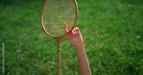 Closeup badminton racket in hands of smiling joyful girl lying on blanket.
