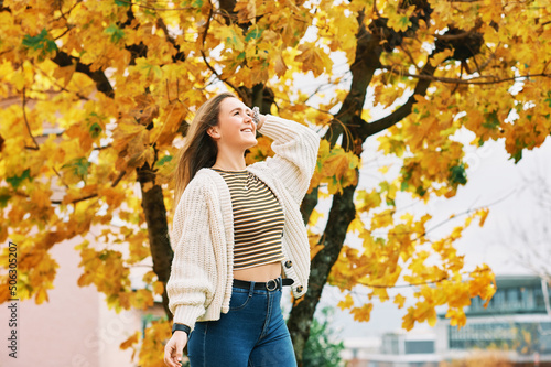 Autumn portrait of young pretty girl posing next to tree with yellow leaves, happy mood and healthy lifestyle