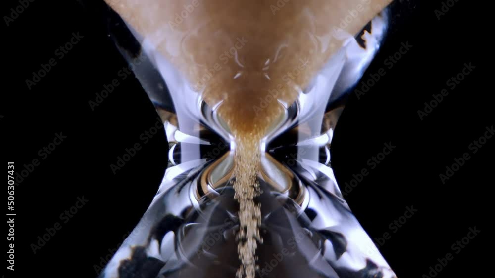 Hourglass. Sands move through hour glass. Sandglass closeup on a black