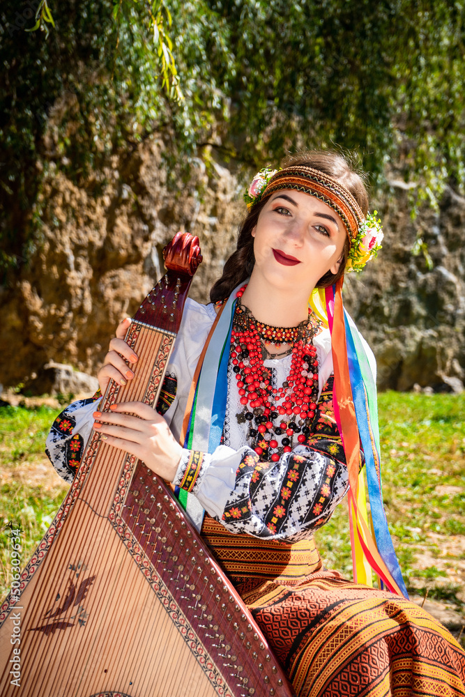 Obraz premium Ukrainian musician in authentic national dress sits by a rock