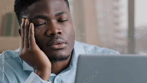Sleepy tired african man office male dreamer businessman has sleeping problem napping rest at desk american lazy student overworked guy in retire closed eyes feeling exhausted after hard computer work photo
