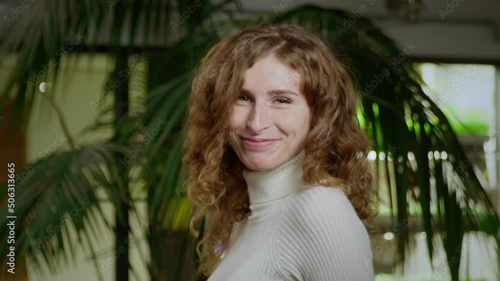 A close-up of a young, very cheerful woman with red hair, turns to the camera from the back. Portrait of a girl A close-up of a young, very cheerful woman with red hair, turns to the camera from the back. Portrait of a girl