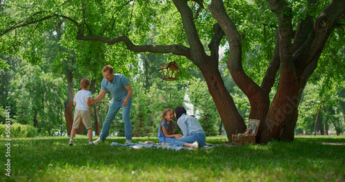 Active family have fun on green park meadow. Parents play with kids outside. photo