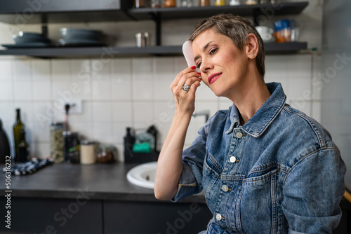 Tableau sur toile One woman mature caucasian female using gua sha rose quartz face massage stone i