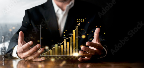 Businessman show golden stock market bar chart grow up to target. Business finance concept. Businessman's hands Show success graph, stocks grow every year and set goals for 2023