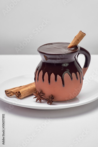 traditional mexican drink based on corn and chocolate served in a clay cup accompanied by cinnamon and anise on a white background photo