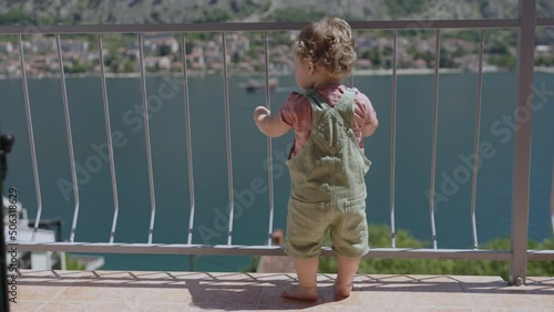 Baby toddler boy standing on balcony at tropical beach resort. family love child person in moring house, happy childhood lifestyle, vacation seaside background, relax view. Silhouette Kid on terrace