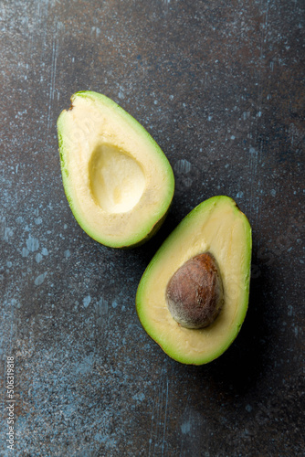 sliced avocado on a dark rustic background background top view, vertical