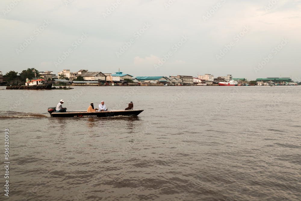 Fototapeta premium Activities of local residents around the Kapuas river: fishing, cycling, and crossing the river using canoes.