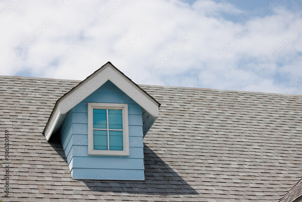 Roof shingles with fake garret house on top of the house. dark asphalt tiles on the roof background on afternoon time.