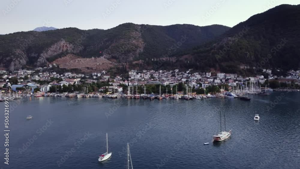 Cityscape of Fethiye filmed from seaside and swimming yachts and boats by drone. Aerial view on coastal town in Turkey next to Mediterranean sea where ships are moving. Famous travel destination theme Cityscape of Fethiye filmed from seaside and swimming yachts and boats by drone. Aerial view on coastal town in Turkey next to Mediterranean sea where ships are moving. Famous travel destination theme