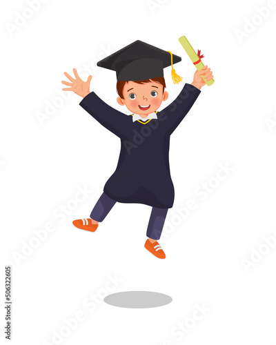 cute little boy student in graduation gown holding certificate diploma jumping in happy graduation day