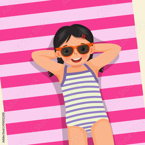 Top view of cute little girl with swimsuit and sunglasses lying on beach towel having fun sunbathing in summer vacation