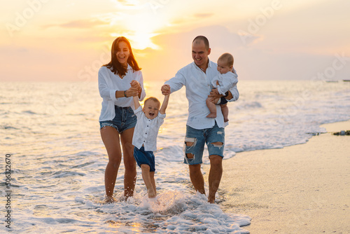 Happy family having fun playing beach in summer vacation on the beach. Happy family and vacations concept. Seascape at sunset with beautiful sky. Family on the beach.