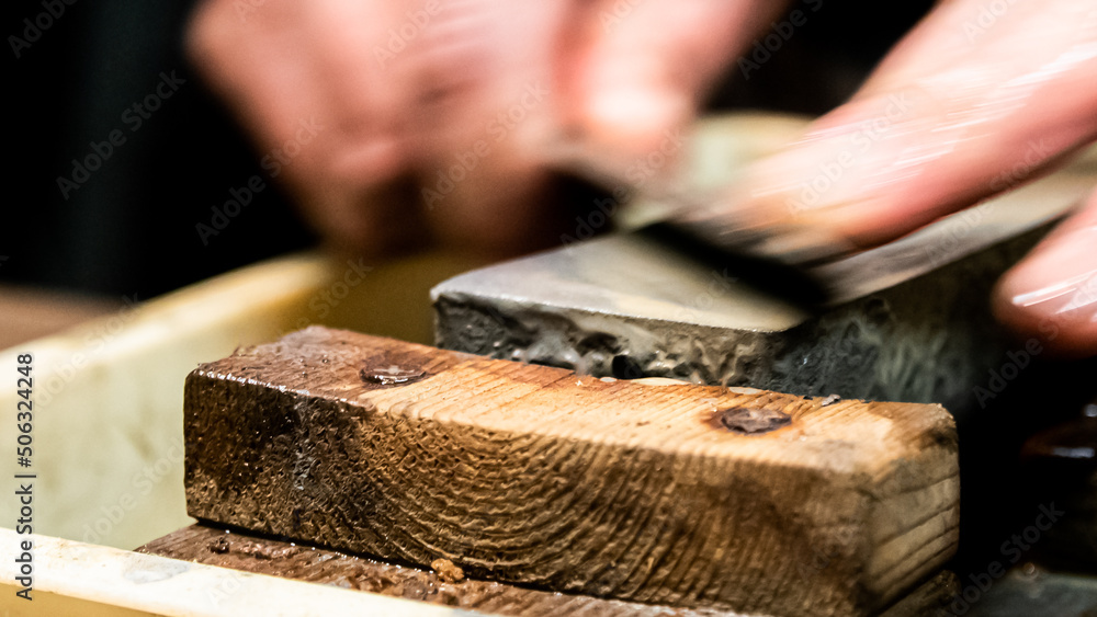 Master swordsmith is sharpening knife on grindstone with water Master swordsmith is sharpening knife on grindstone with water