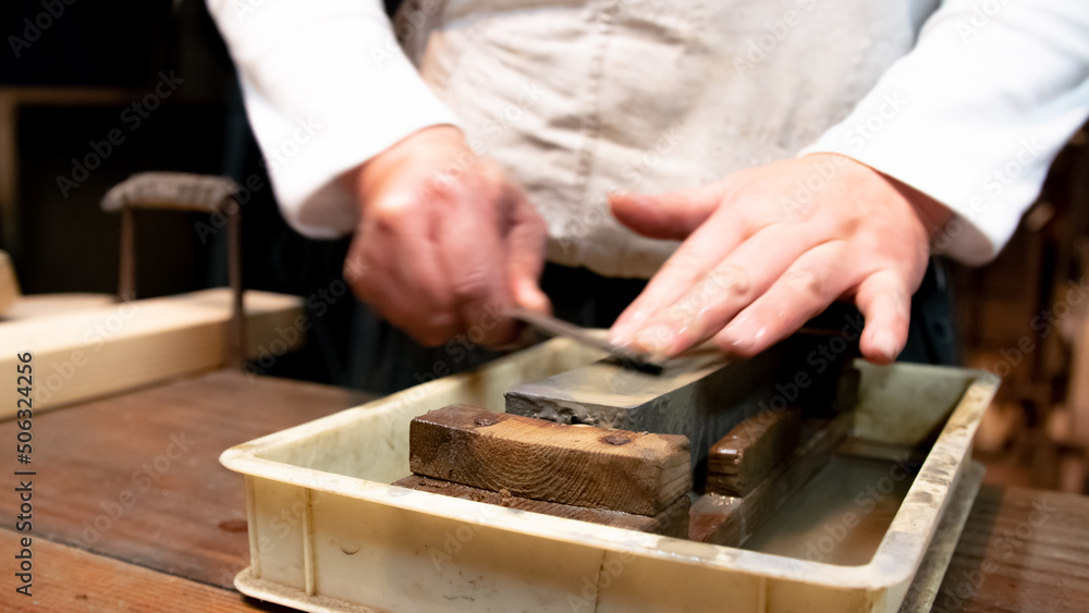 Master swordsmith is sharpening knife on grindstone with water Master swordsmith is sharpening knife on grindstone with water